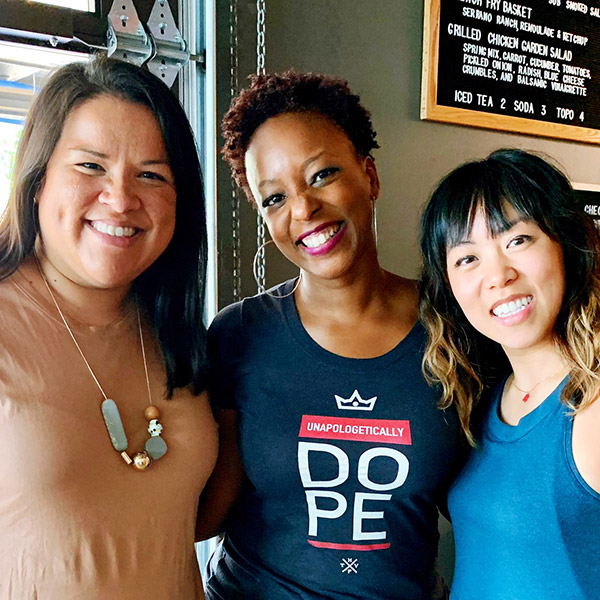 Austin therapists of Color leaders photo. Vanessa, Latina woman, Jenn Minor, Black woman, and Melody Li Asian womxn smiling holding each other and smiling at camera