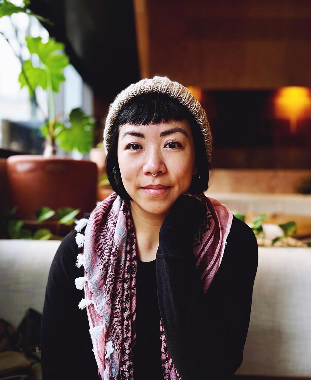 Melody Li, founder of Inclusive Therapists and Mental Health Liberation.  early-midlife nonbinary Hong Konger with short black hair, blunt bangs. First photo, wearing a knitted toque, black shirt, and a red & black keffiyeh. 